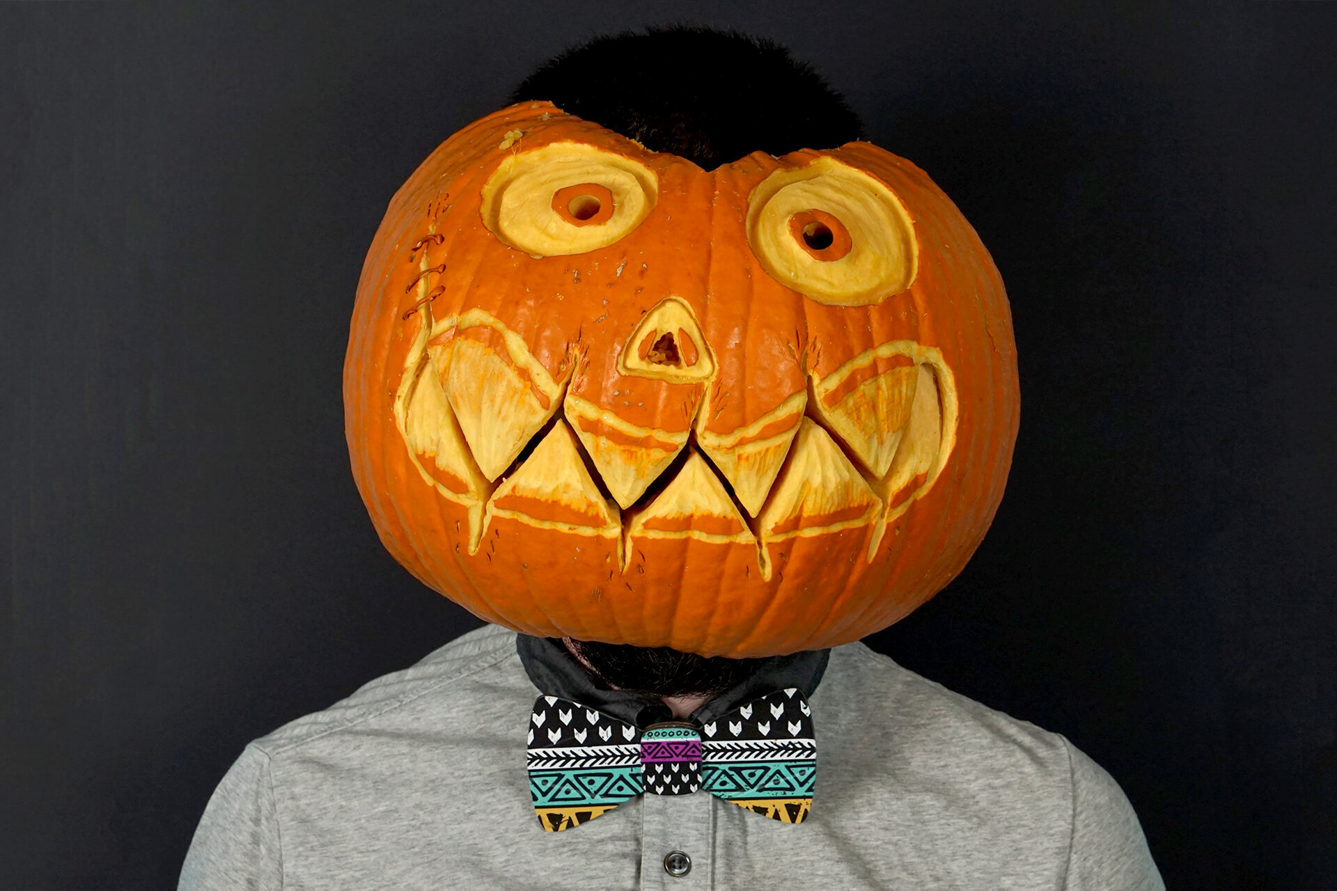 A lifestyle shot of the cardboard doodle bow tie on someone wearing a pumpkin head.
