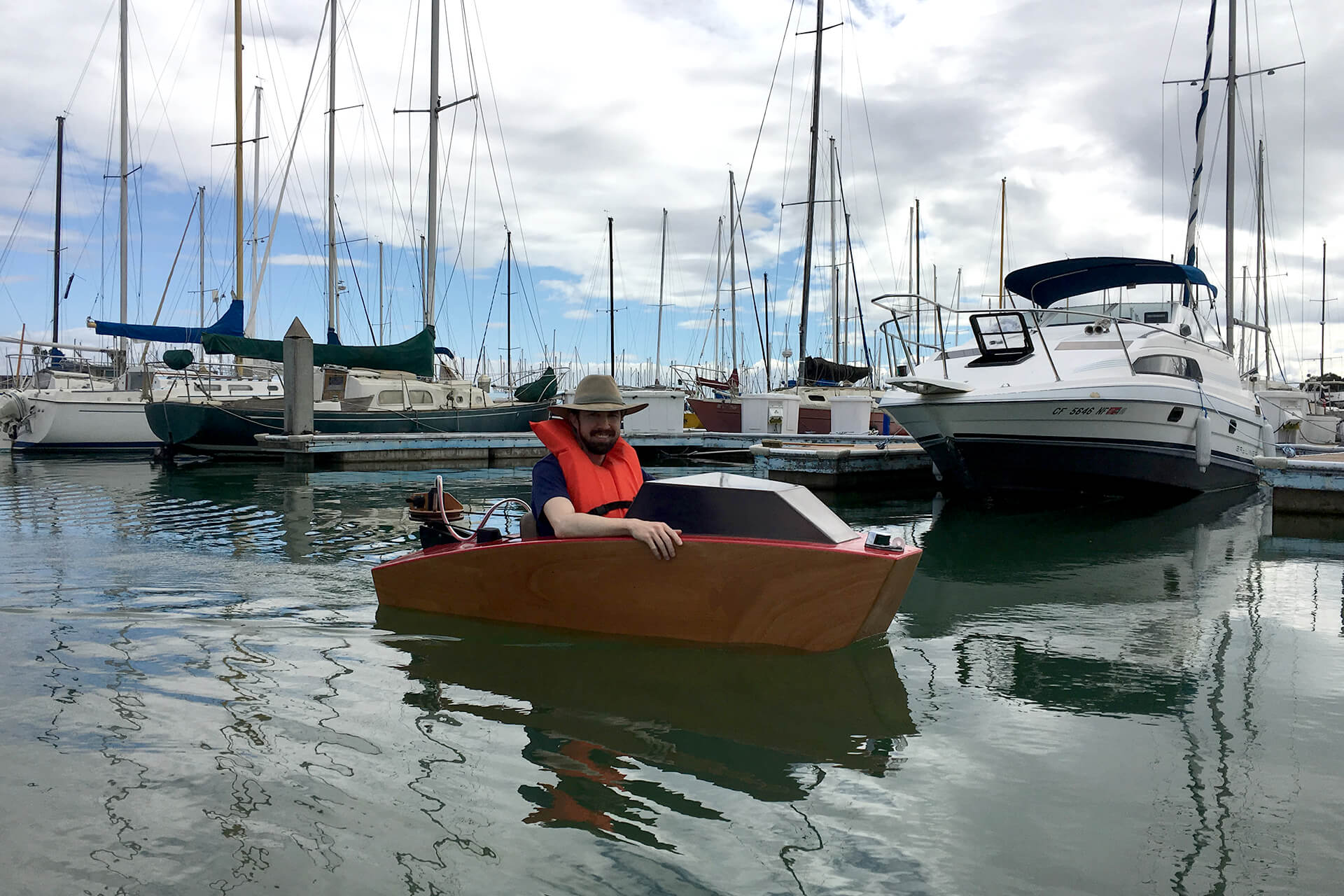 A mini boat cruising in the Emeryville harbor on a calm day.