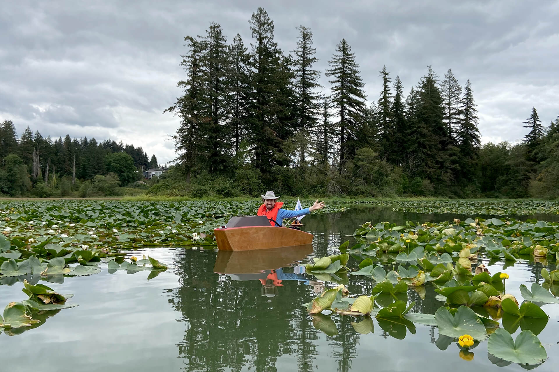 A mini boat in the middle of a large lily pad forest.